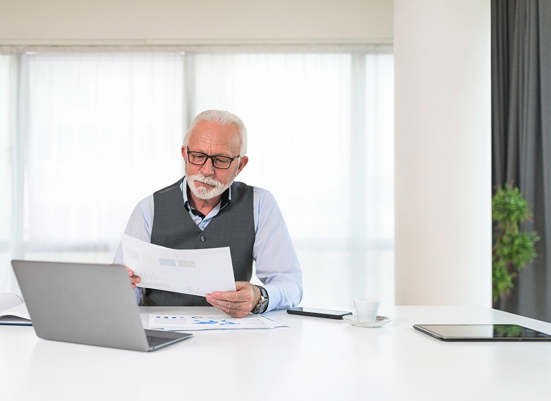 Business Insurance - Smiling Senior Manager Looking at Business Reports in an Office